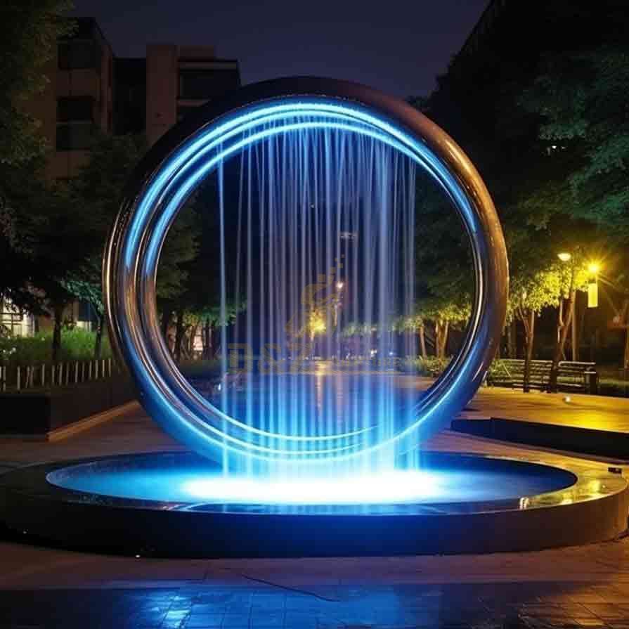 Large circular fountain sculpture in the park, rain curtain spray effect, lighting design